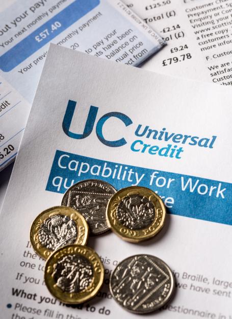 UK Universal Credit form with British coins and unpaid utility bills.
