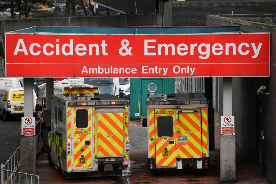 Ambulances parked under an "Accident & Emergency Ambulance Entry Only" sign at a hospital.