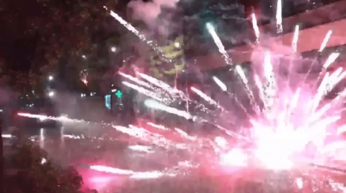 Fireworks exploding on a street at night.