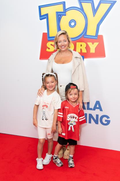 Kelsey Parker with her children, Aurelia and Bodhi, posing in front of a "Toy Story" sign.