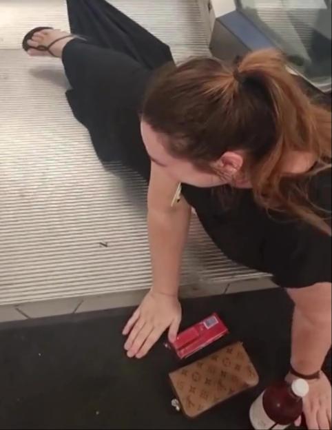 A woman on an escalator is entangled in her long black dress, with a TikTok comment box overlaying the top left corner that reads, "I'm sorry, but I need to see the video."