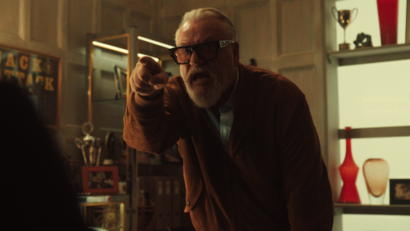 Ray Winstone as Bobby Glass, an older man with glasses and a white beard, points a finger while speaking.