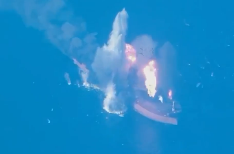 A ship on fire and exploding in the middle of the ocean.