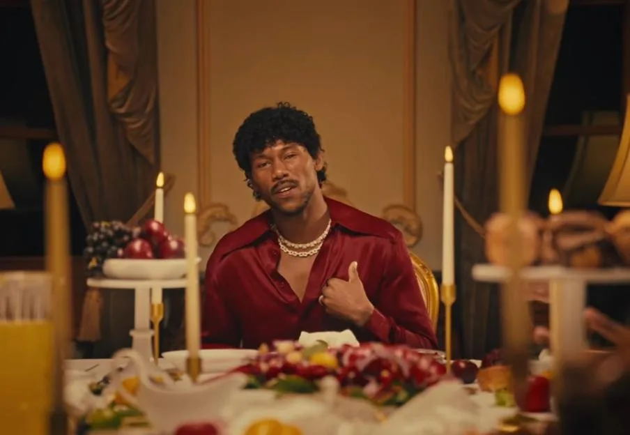 King Kenny sitting at a candlelit dining table in a still from his "Don't Let Me Down" music video.