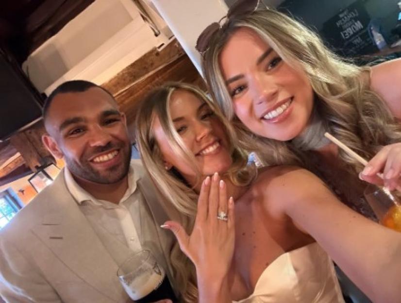 Three friends smiling for a selfie, one woman showing an engagement ring.