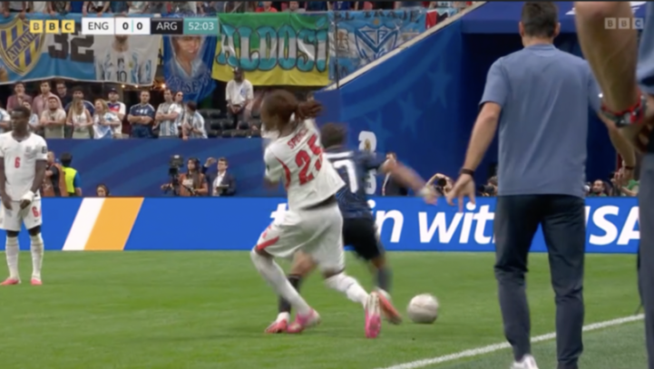 A soccer player in a white uniform with "SPENCE 25" on the back attempting to kick a ball on a green field.