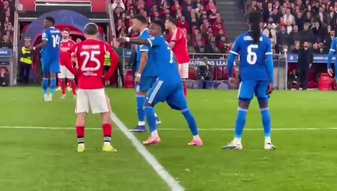 Soccer players on a green field, some wearing blue uniforms and some wearing red and white.