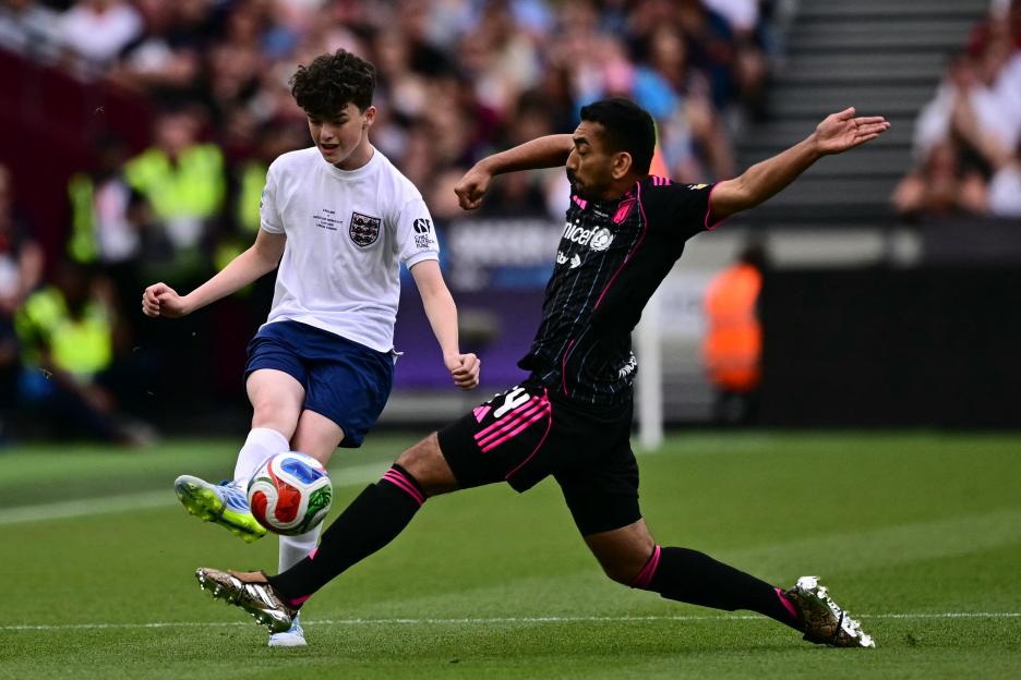 Two soccer players, one in a white shirt and one in a black and pink shirt, battling for the ball.