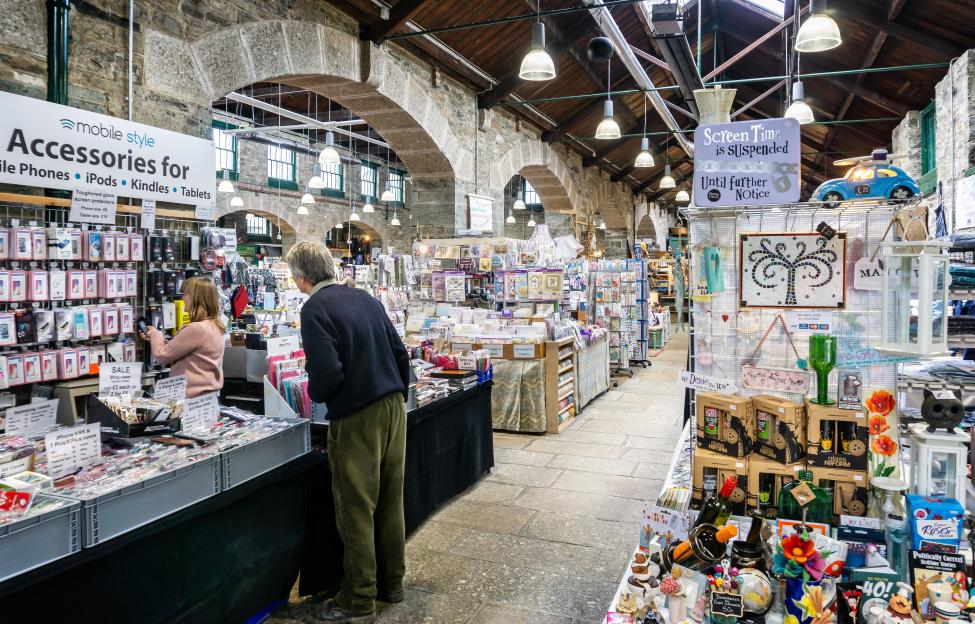 Shoppers browsing at stalls in the ancient Pannier Market in Tavistock.