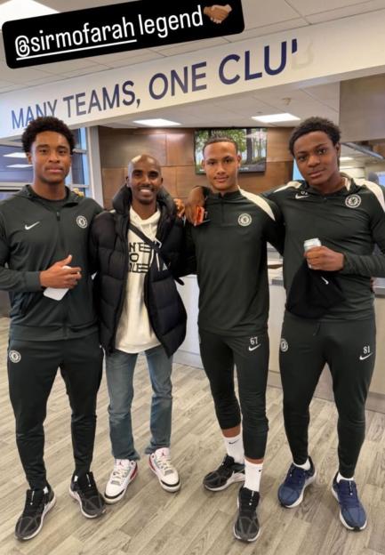 Mo Farah posing with three young athletes in a hallway.