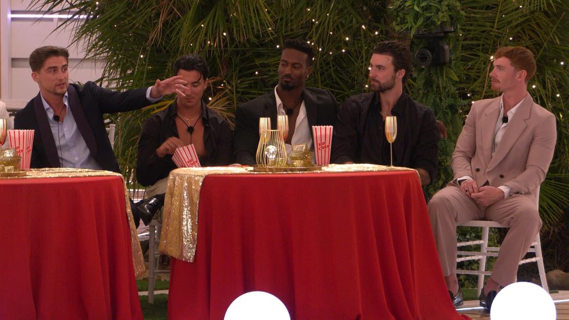 Five male "Love Island All Stars" actors seated at two red tables with gold accents.