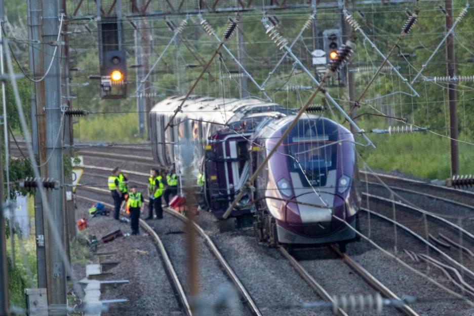 Emergency workers attend to the Bedford train crash where carriages are derailed.