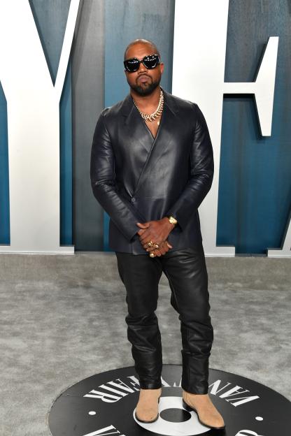 Kanye West in a black leather suit, chunky gold necklace, and black sunglasses at the Vanity Fair Oscar party.