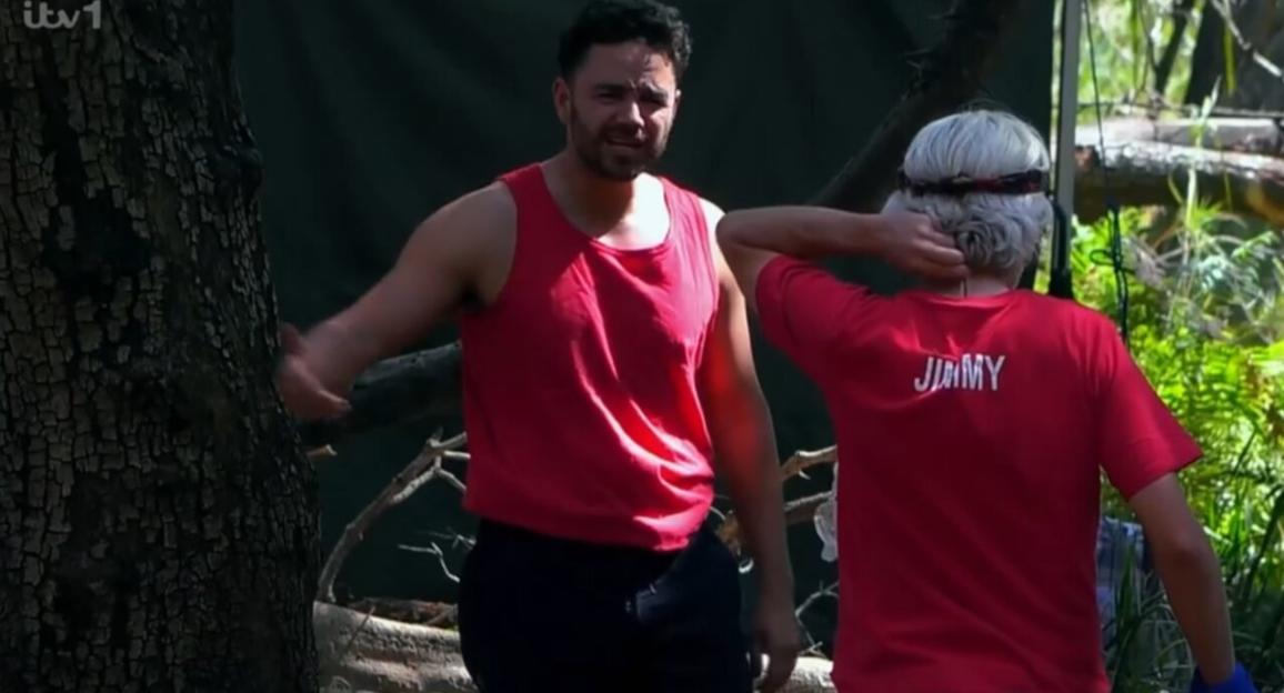 Adam Thomas in a red tank top with another person from behind.