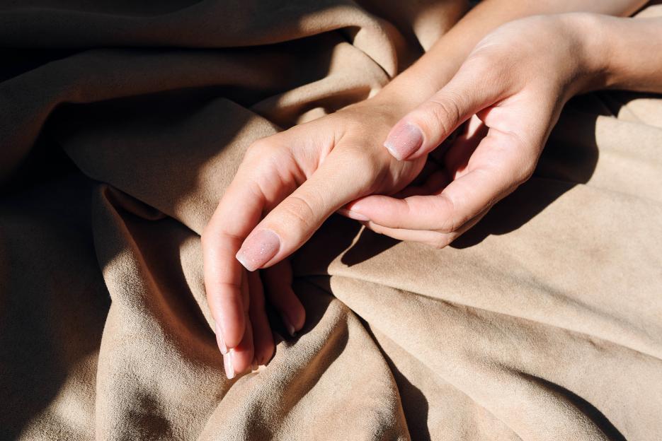 Female hands with gentle manicure on a fabric background.