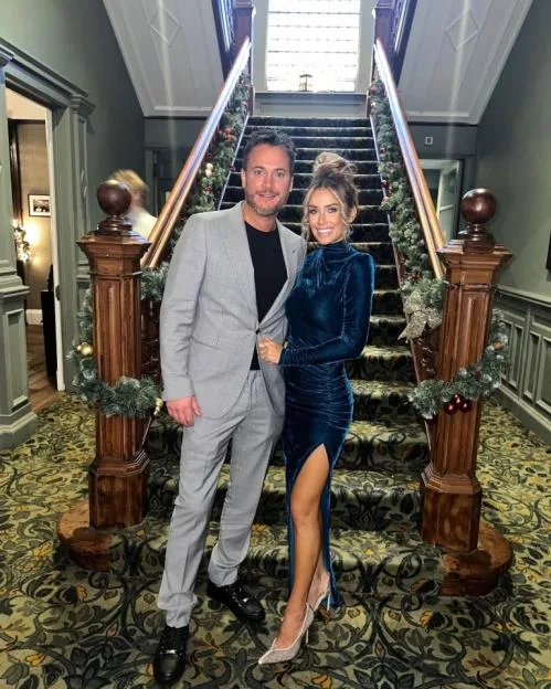 Laura Anderson and Gary Lucy standing on a decorated staircase.