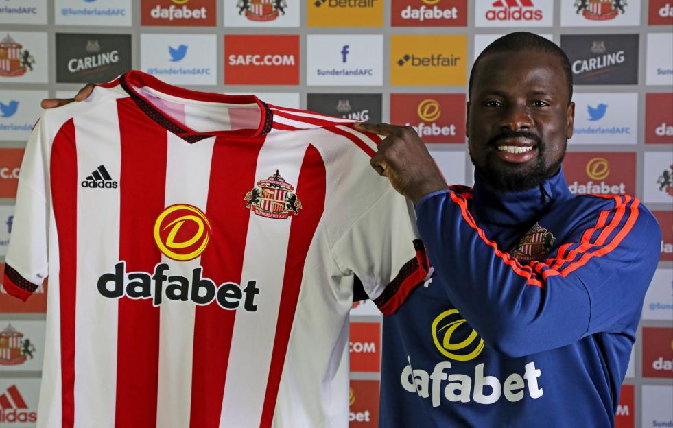 Emmanuel Eboue holding up a Sunderland AFC club shirt.
