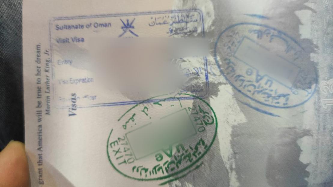 Close-up of passport and visa documents, including entry and exit stamps from Oman and the UAE.