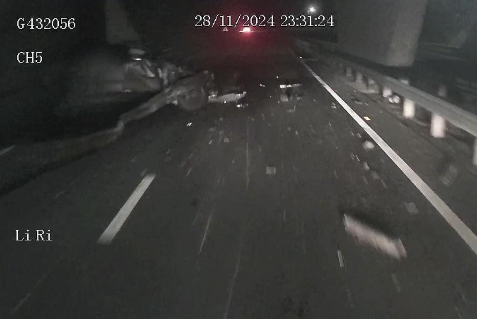 Debris from a car crash scattered across a dark highway at night.