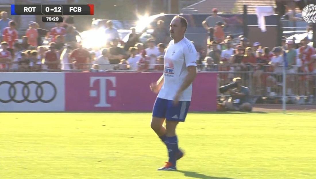 A soccer player in a white and blue uniform stands on a green field with a scoreboard showing "ROT 0-12 FCB" and the time 79:29.