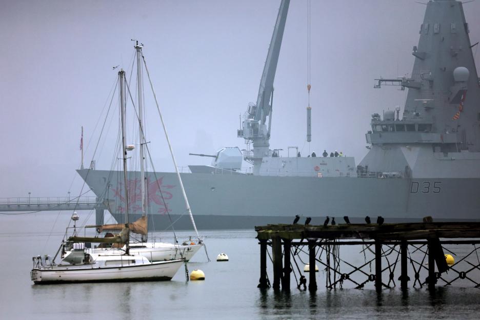 A crane loads equipment onto HMS Dragon, a Royal Navy Type 45 Daring-class air-defence destroyer warship, in Portsmouth Harbour.