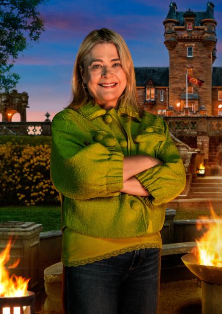 Harriet, a 52-year-old Crime Writer and Former Barrister from London, poses outdoors with a stately building and two fire pits in the background.