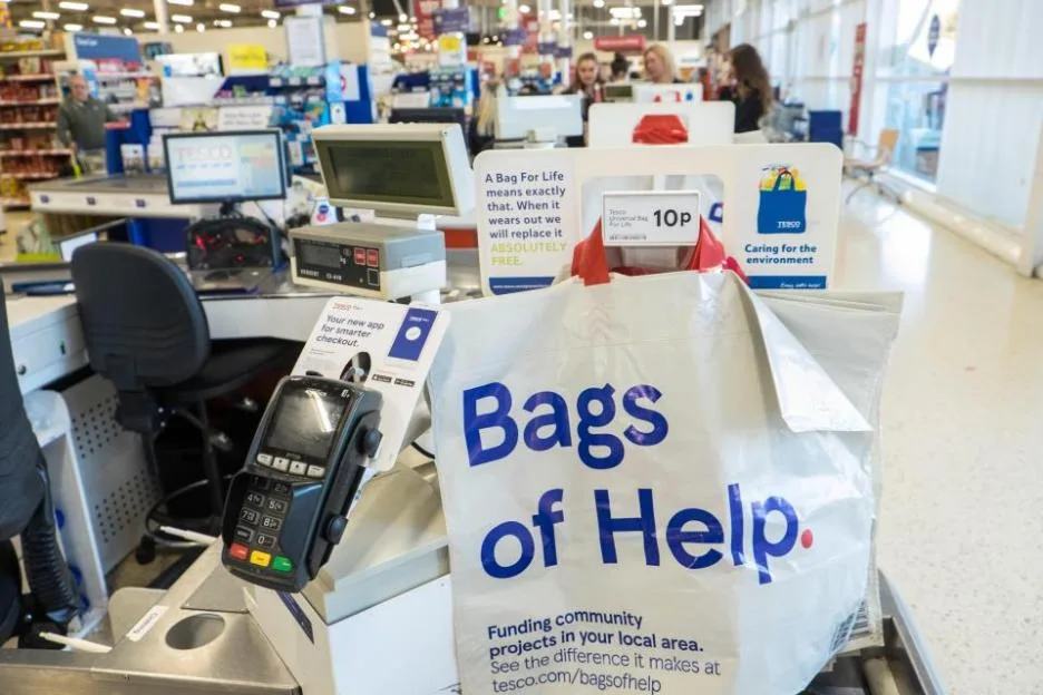 A Tesco checkout area displays a multi-use plastic bag for life on the counter.