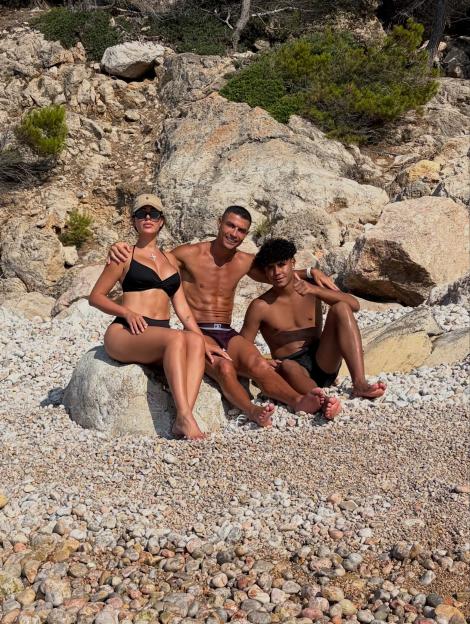 Cristiano Ronaldo, Georgina Rodriguez and Cristiano Ronaldo Jr. relaxing on a rocky beach.