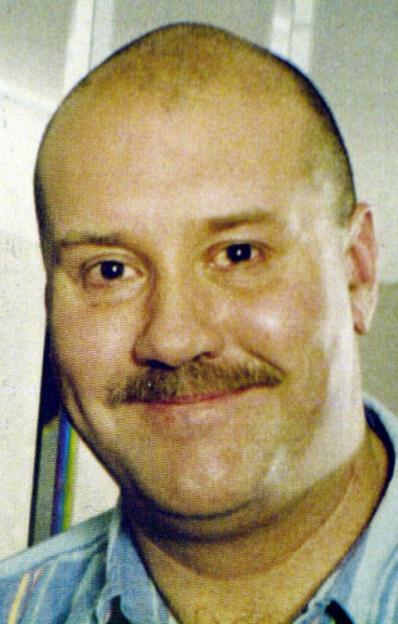 Headshot of a smiling man with a shaved head and a mustache.