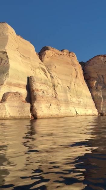 Rock formations along a body of water under a clear blue sky.