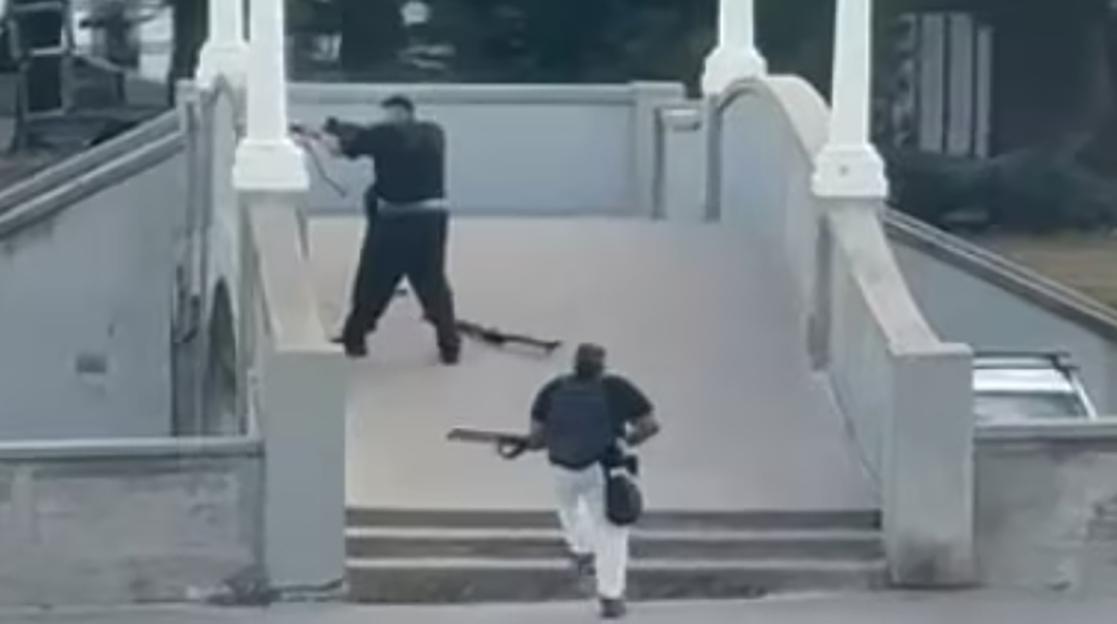 Two gunmen on a concrete overpass.