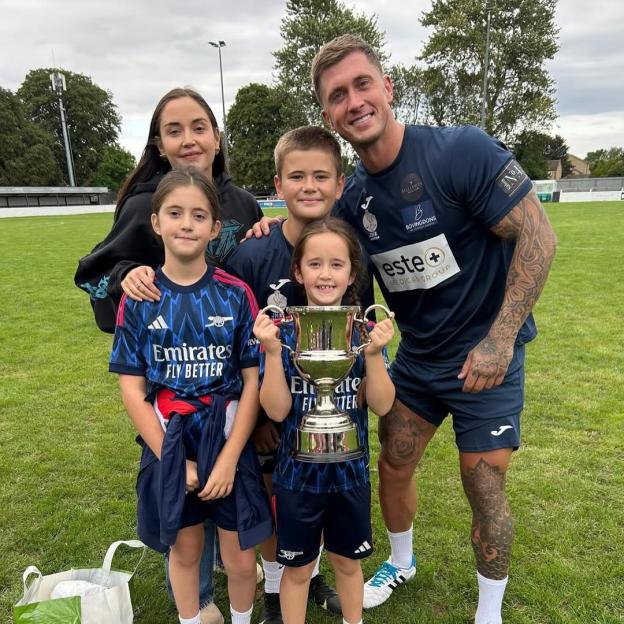 Jacqueline Jossa, Dan Osbourne, and their three children standing on a soccer field.