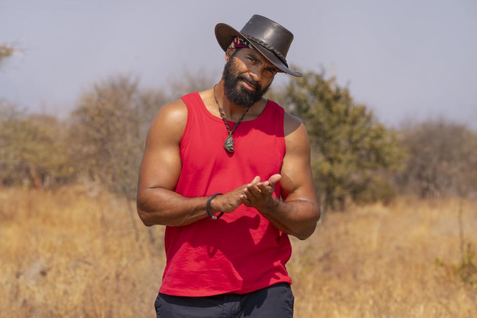 Former champion boxer David Haye in a red tank top and brown hat, with his hands clasped together.