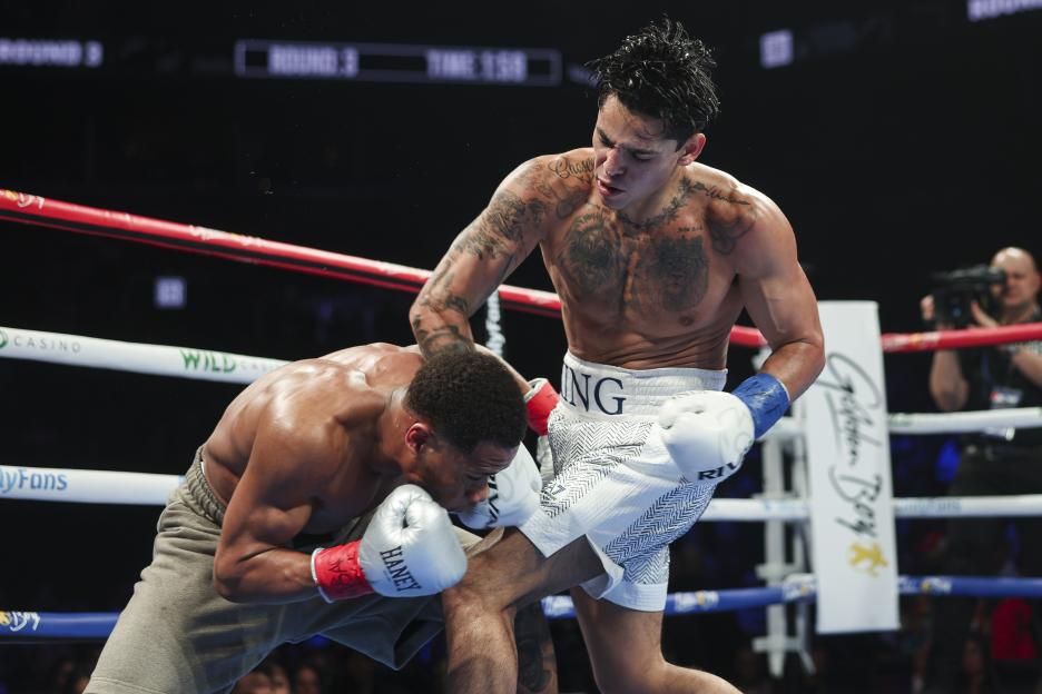 Devin Haney defends a punch from Ryan Garcia during a boxing match.