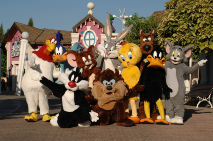 Mascots of Looney Tunes characters including Bugs Bunny, Daffy Duck, Tweety, Sylvester, Taz, Foghorn Leghorn, Road Runner, and Tom and Jerry at Parque Warner Madrid.