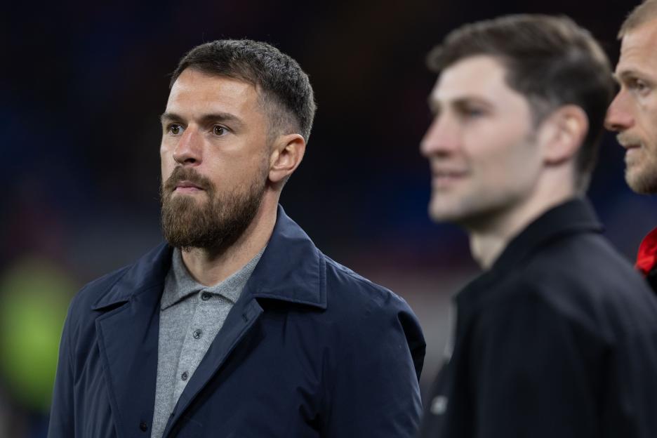 Aaron Ramsey of Wales in a dark jacket and grey polo shirt.