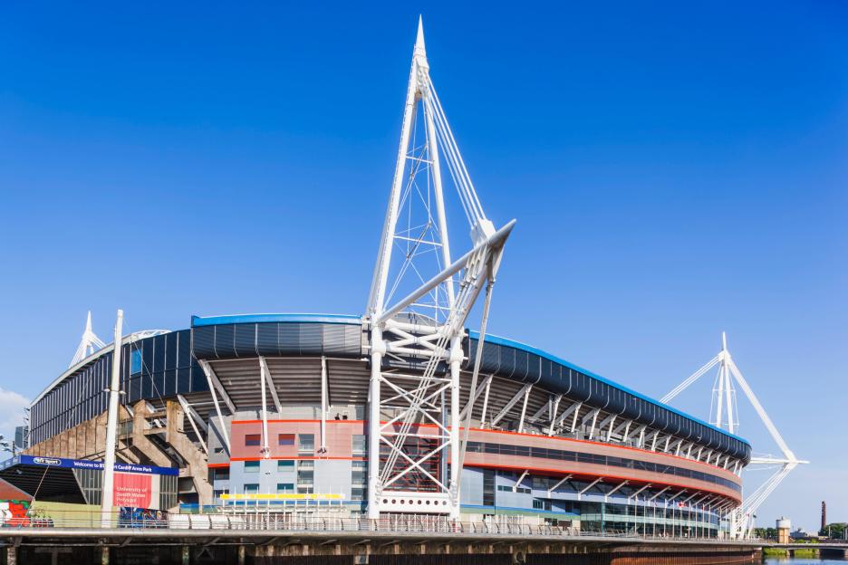 Exterior view of the Principality Stadium in Cardiff, Wales, with a bright blue sky.