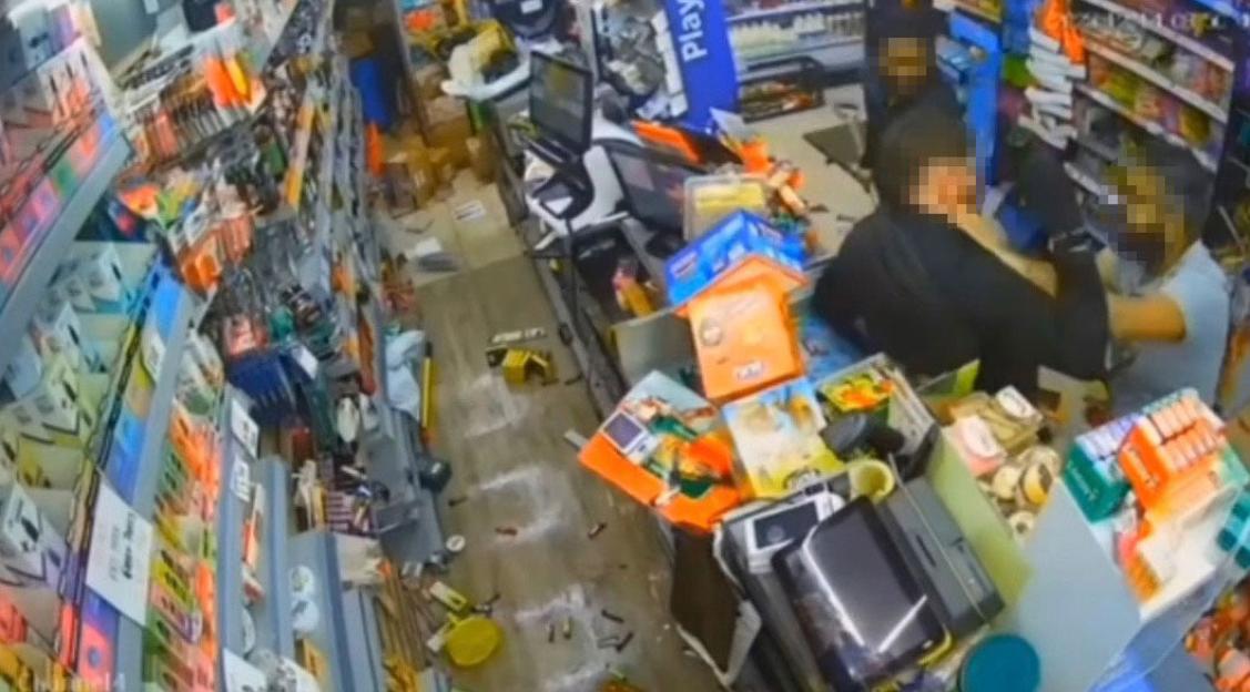 CCTV footage of a shopkeeper confronting a hooded individual in a ransacked store.