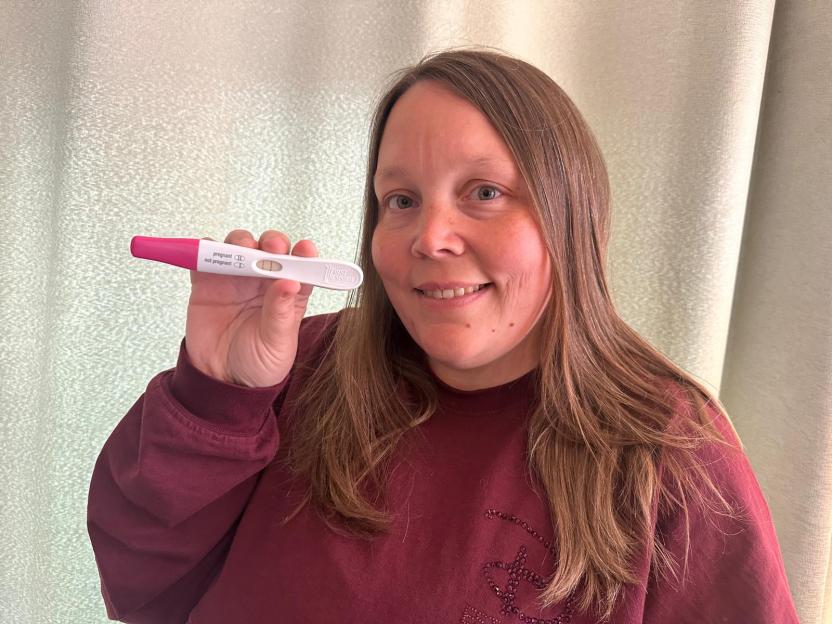 Becky Harris holding up a positive pregnancy test.