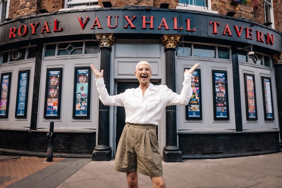 Danny Beard stands outside the Royal Vauxhall Tavern, arms outstretched, celebrating their role in "Savage," a play about Paul O'Grady's drag alter ego, Lily Savage.