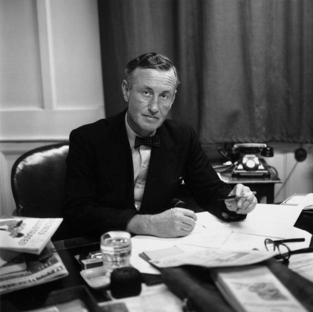 Ian Fleming, British author and creator of James Bond, at his desk in his study.