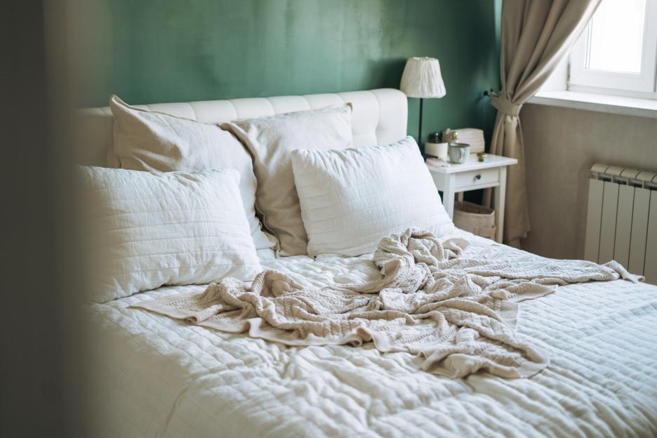 Modern bedroom interior with a stylish made bed, natural light, and minimalist decor details