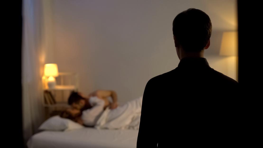 Man discovering his wife with another man in bed.