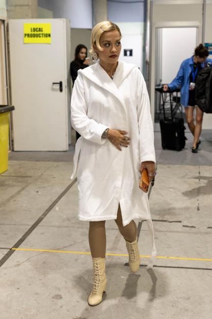 Rita Ora leaving Spain's Gozo Festival in a white dressing gown after her performance was cancelled due to a thunderstorm.