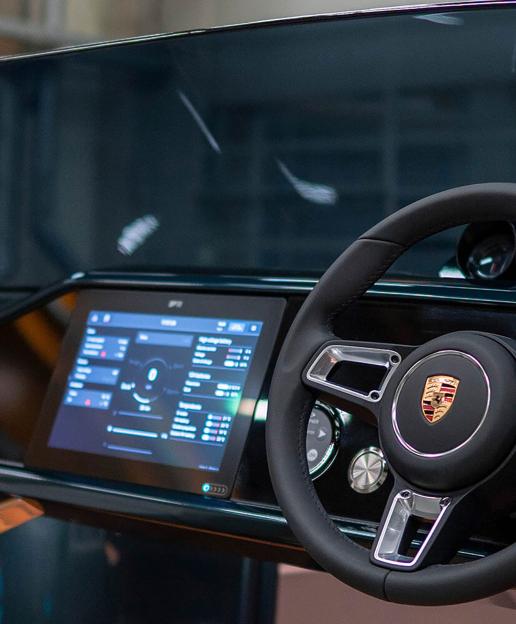 A steering wheel with a Porsche logo and a digital display showing boat controls.