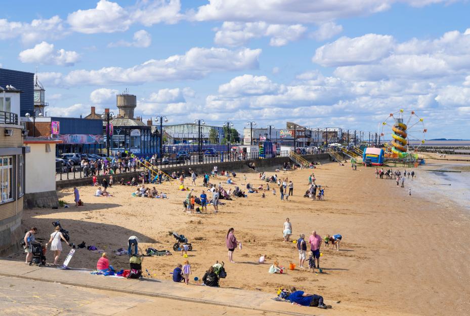 Cleethorpes beach with funfair and many people enjoying the day.