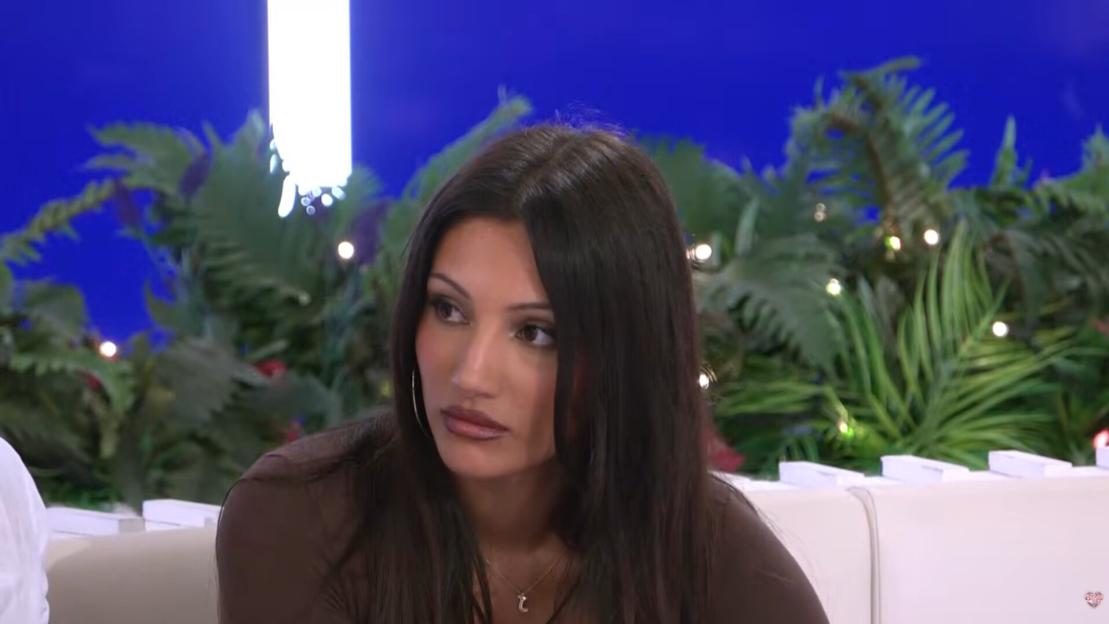 A woman on Love Island looks on with a tense expression.