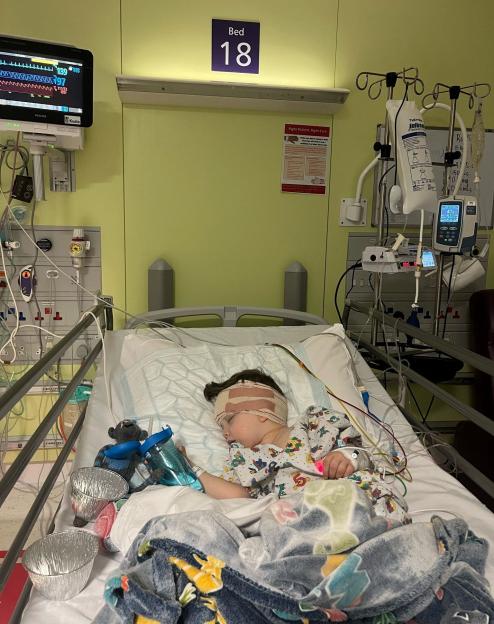 Raffi Starkowitz after surgery in hospital, with bandages around his head and connected to medical equipment.