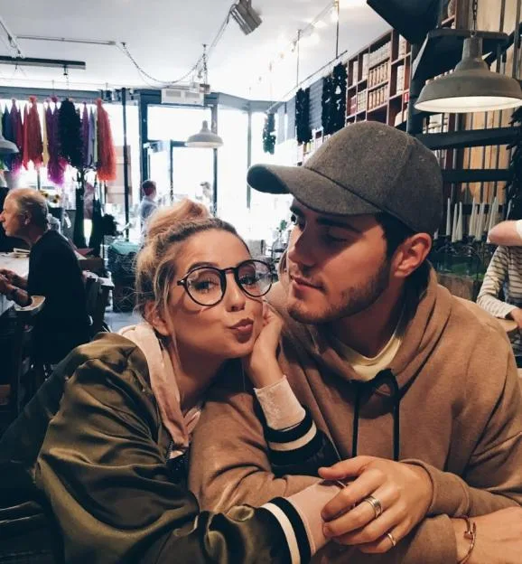 Zoe Sugg and Alfie Deyes sitting together indoors.