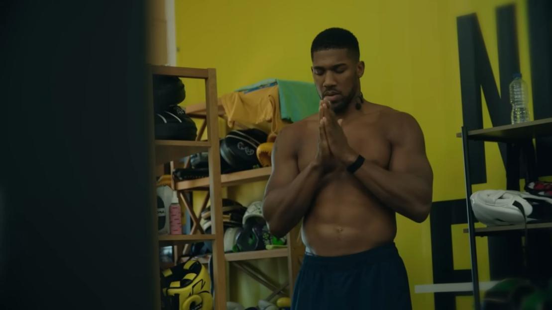 Anthony Joshua with his hands pressed together in a meditative pose.